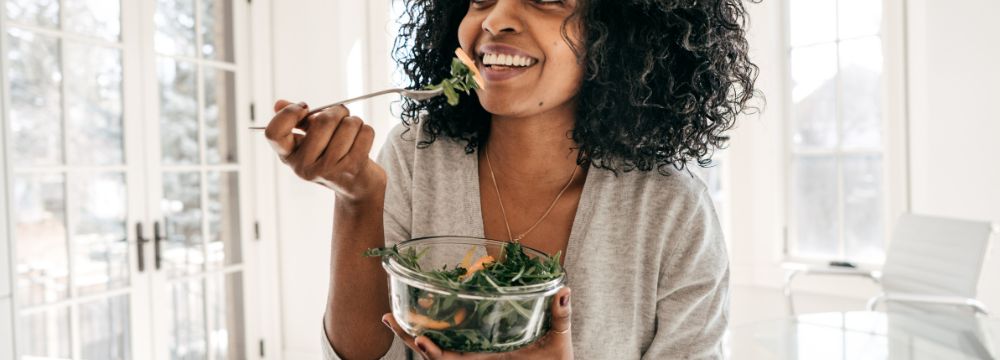 Woman eating salad while smiling