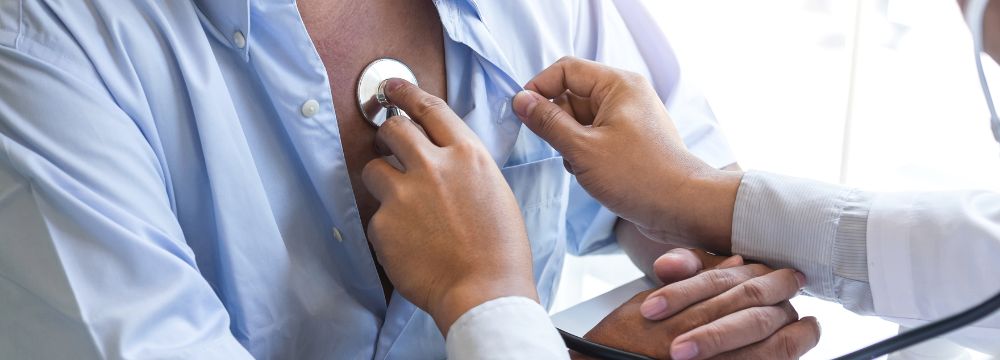 Doctor listening to male patients heartbeat